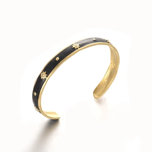 Detailed macro view of gold plated cuff bracelet with black enamel and star engraving