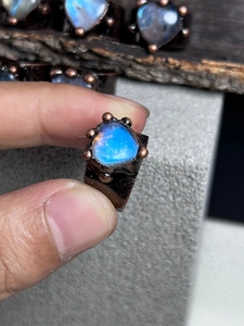 Close-up of handmade bronze ring featuring a natural heart-shaped blue moonstone on hand