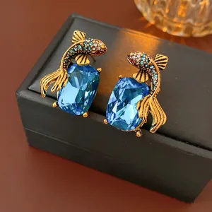 Vintage style gold-plated goldfish earrings with colorful crystals on a black leather box
