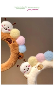 Close-up of soft plush caterpillar headbands in brown and beige with colorful pom-poms