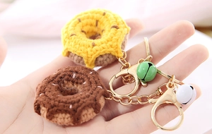 Close-up of handmade crochet donut keychains with gold metal rings and small bells