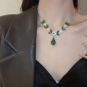 Dettaglio di una modella con parure di collana e orecchini a goccia con zirconi verdi