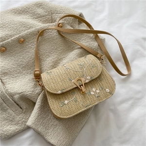 Détail du sac selle tissé beige avec broderie florale et boucle en métal doré chic