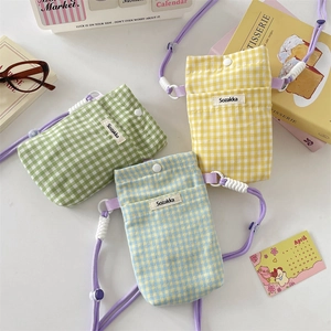 Close-up of checkered fabric phone bags in green, yellow and blue with purple cords