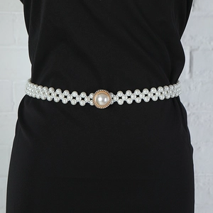 Close-up of white faux pearl waist chain with a gold rhinestone buckle on the dress