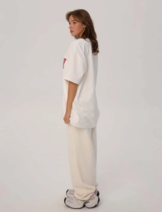 Vista laterale della t-shirt oversize in cotone bianco con stampa di lettere rosse