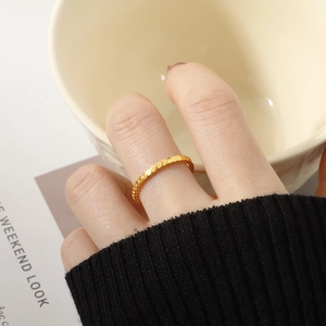 Close-up of a gold geometric fish-scale textured titanium steel ring on a finger