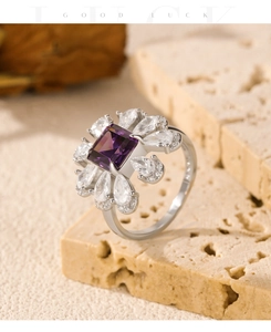 Macro detail of silver flower ring with square violet stone and pear-cut zircon accents