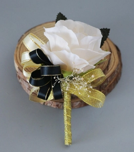 Détail d'une boutonnière faite main en rose blanche avec ruban doré sur socle en bois