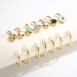 Detail of gold-plated open rings with colorful floral accents and faux pearls