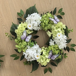Detail of autumn hydrangea wreath with daisies, green leaves and purple butterflies