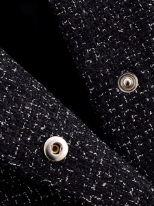 Detail of black tweed fabric texture with white weave and silver metal button snap