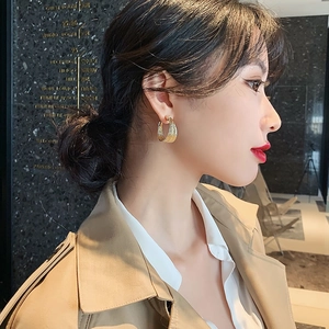 Close-up of layered golden multi-hoop earrings worn by a model on a luxury background