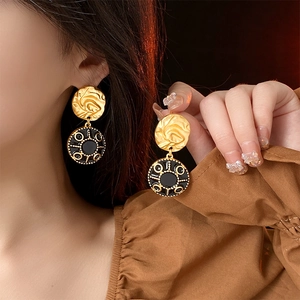 Macro detail of vintage gold and black enamel round earrings worn on ear