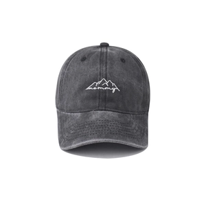 Detailed view of white mommy mountain embroidery on washed black denim baseball cap