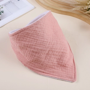 Close-up of pink double-layer cotton gauze baby bib with soft wrinkled fabric texture