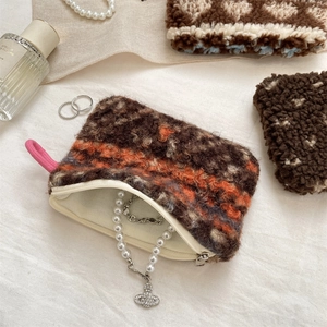 Detail of plush geometric pouch with vintage Saturn pendant pearl necklace inside