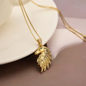 Gold-plated horse pendant necklace with colorful zircon gemstones on a ceramic tray