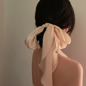 Close-up of a soft pink chiffon hair ribbon tied in a large bow on an elegant updo hairstyle