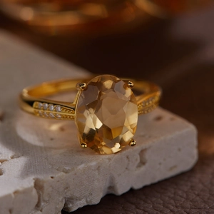 Macro shot of an oval yellow citrine silver ring with diamonds on a textured stone