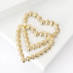 Elegant gold heart brooch with textured hollow design and rhinestones on white block