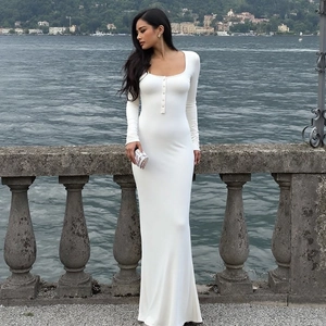 Détail de la robe moulante blanche à manches longues avec décolleté en U boutonné