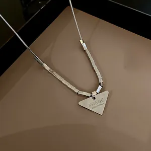 Dettaglio macro del ciondolo a triangolo in acciaio argento con incisione su catena snake