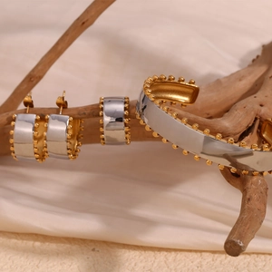 Close-up of dual-tone jewelry set with golden beaded edges on natural wood background
