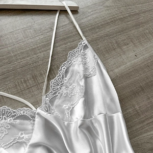 Elegant white satin camisole with floral lace neckline on a natural wood background