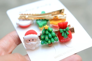 Detail of Christmas hair clips featuring Santa and tree on white display card