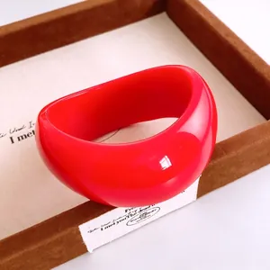 Auffälliger roter Acryl-Armreif in klobigem Design mit Hochglanz-Finish auf einem Tablett
