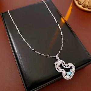 Detailed view of silver necklace with hollow heart pendant featuring pearl and blue zircon