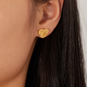 Fashionable gold-plated heart stud earrings for women shown worn on the earlobe
