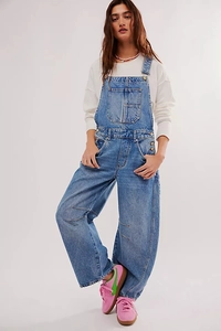 Detail of adjustable straps and large chest pocket on washed denim overalls