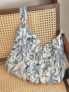 Vintage blue floral canvas shoulder bag displayed on a rustic wooden rattan chair