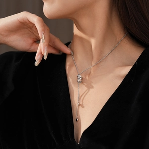 Detail of silver Y-shaped tassel necklace with cylinder slider and heart pendants