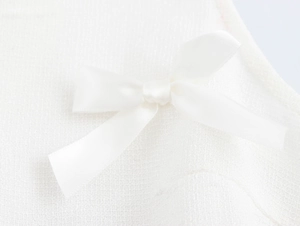 Détail d'un nœud en ruban blanc cousu sur le tissu texturé d'une robe col en V