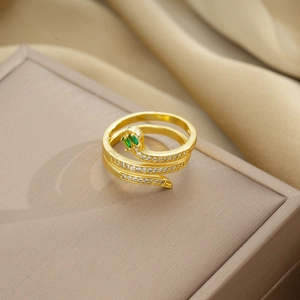 Macro shot of gold snake ring with green emerald eyes and pave diamonds on jewelry box