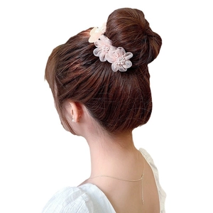 Elegant pale pink floral hair clip with pearl accents on minimalist bun hairstyle