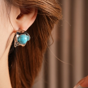 Close-up of vintage silver C-shaped earring with blue turquoise on a female model