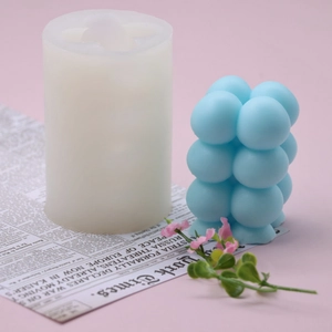 DIY silicone bubble cube mold and blue decorative candle on vintage newspaper background