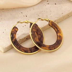 Close-up of stylish amber resin hoop earrings with elegant gold metal buckles