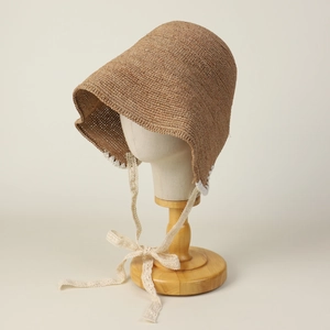 Detail of hand-woven raffia sun hat with delicate white lace ribbons and crochet trim