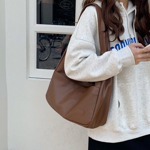 Große braune PU-Leder Einkaufstasche mit breitem Gurt am Modell in lässigem Stil