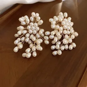 Elegant cluster flower pearl stud earrings with handcrafted golden wire on wood tray