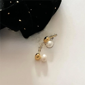 Detail of round white pearl earrings with golden metal sphere on a vintage book page