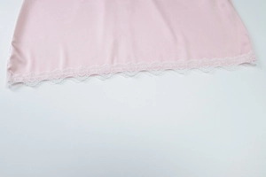 Close-up of pink satin dress hem featuring delicate white lace trim on white background