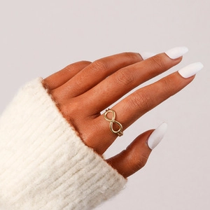 Detail of a minimalist gold-plated infinity open ring worn on a finger with knit texture