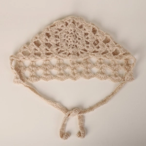 Macro detail of beige hand-crocheted mohair bonnet with floral lace and side ties