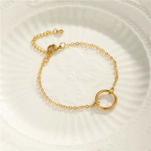 Detail of 18K gold-plated geometric bracelet with round pendant on ceramic plate